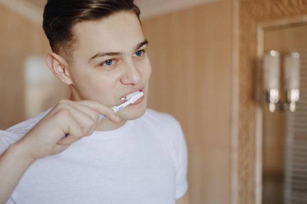 A man brushing his teeth in a white t shirt