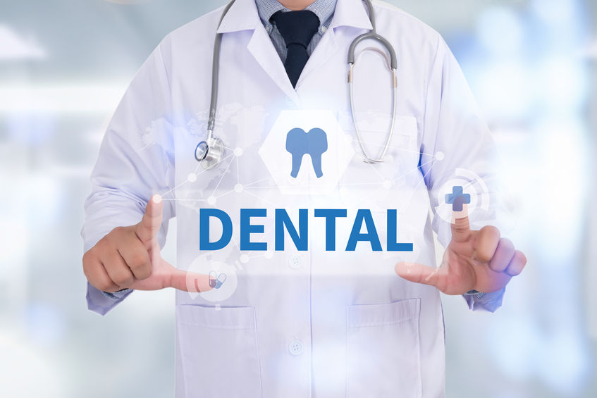 A man in a lab coat holds up a sign that says "Dental"